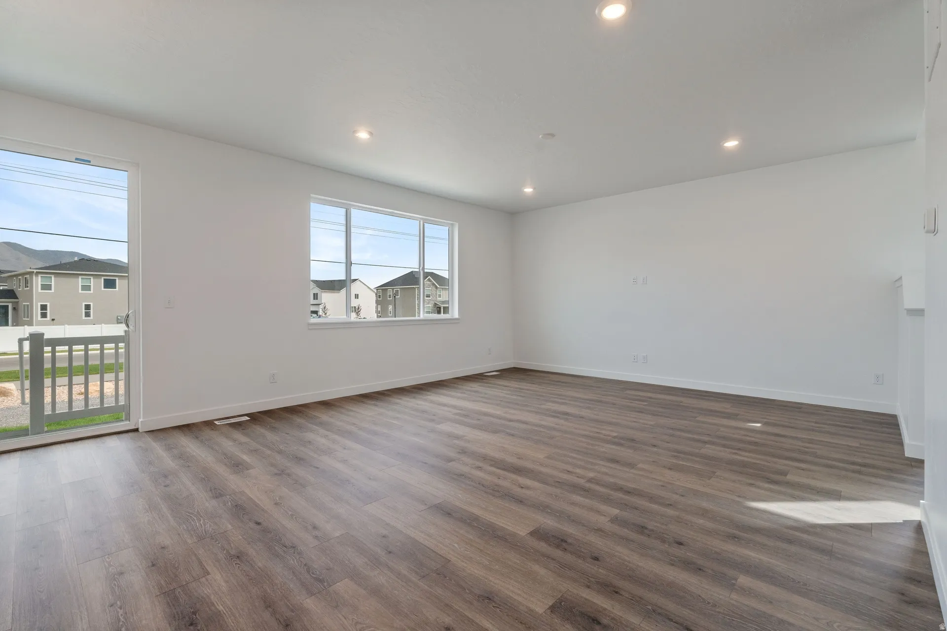 Spacious interior featuring wood-finish flooring, white walls, and recessed lighting