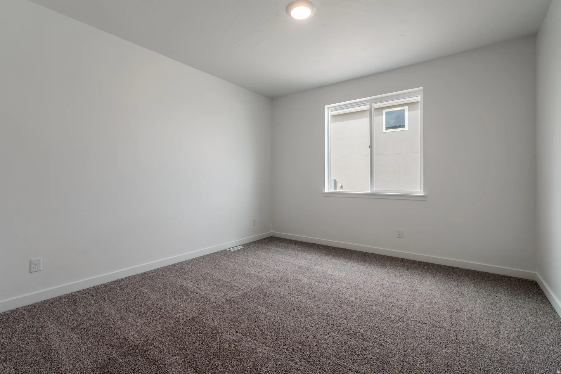 Carpeted room featuring a single window with white trim, a flush-mount ceiling light, and white baseboards