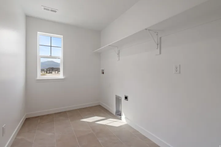Utility room featuring light-colored tile flooring, white walls, and a window with mountain scenery