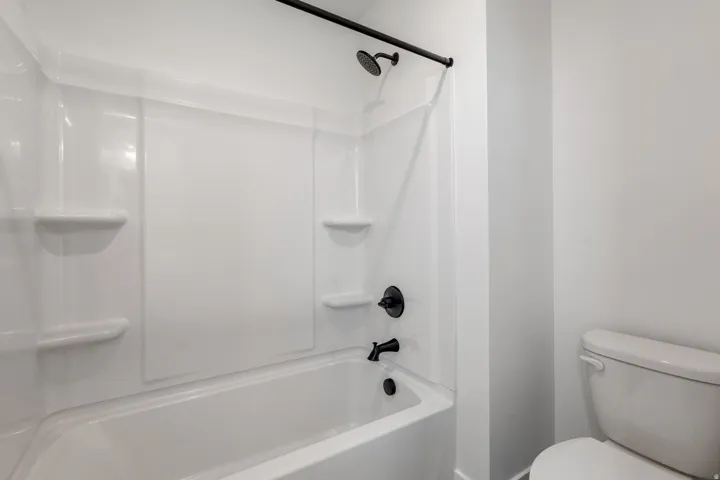White fiberglass tub and shower combination featuring integrated shelving