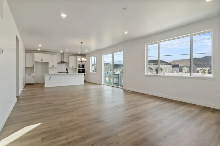 Open-concept living space featuring wood-finish flooring, recessed lighting, and a white kitchen with a central island