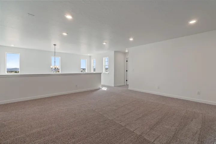 Spacious upper-level area with neutral-toned carpet and recessed lighting