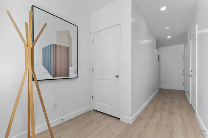 Entryway featuring wood-finish flooring, white paneled doors, and recessed lighting