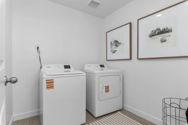 Dedicated laundry space featuring wood-finish flooring, white walls, and a recessed ceiling light