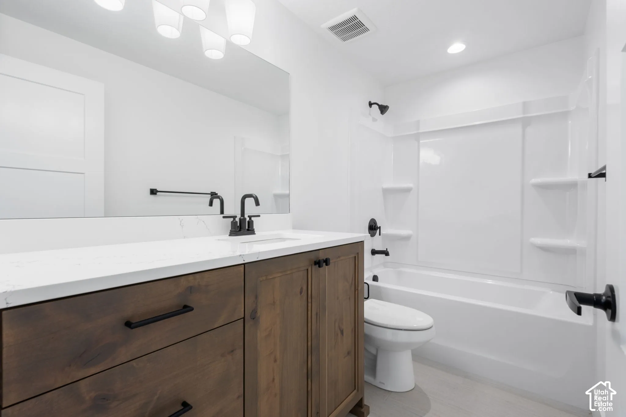 Wood-finish vanity with a white stone-finish countertop, matte black faucet, and rectangular undermount sink
