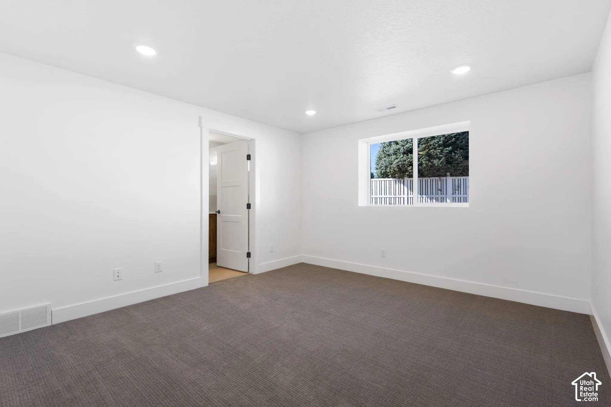 Neutral wall finishes, recessed lighting, carpet flooring, and a single window