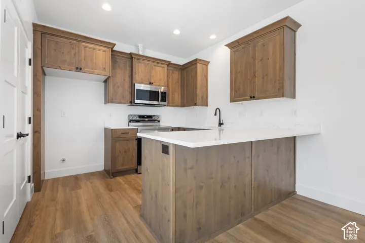 Kitchen featuring wood-finish cabinetry, stainless steel microwave, and a matte black faucet