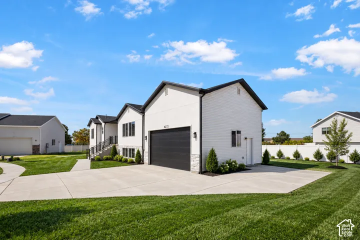 Modern exterior featuring white siding, black-trimmed windows, a black garage door, and a stone accent foundation