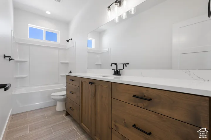 Wood-finish vanity with a white countertop and undermount sink in expansive bathroom.