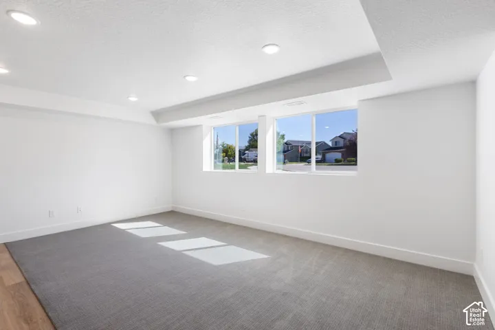 Recessed lighting, wood-finish flooring, gray carpet, and two large windows