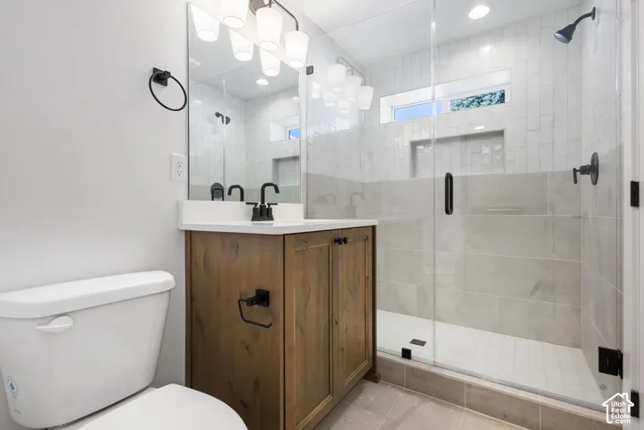 Frosted glass shower enclosure, wood-finish vanity with countertop, rectangular undermount sink, and matte black fixtures
