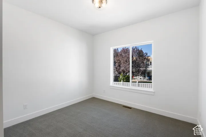 Neutral white walls and ceiling, gray carpet flooring, contemporary light fixture, and a large window with white trim