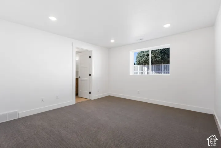 Neutral wall finishes, recessed lighting, carpet flooring, and a single window