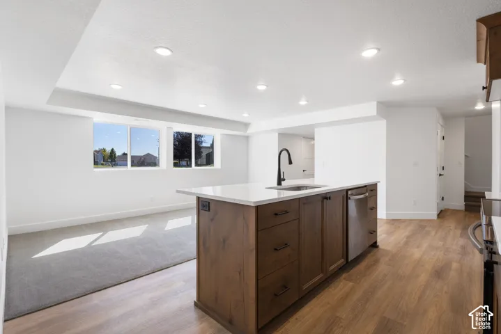 Kitchen island with wood-finish cabinetry, white countertop, and stainless steel dishwasher
