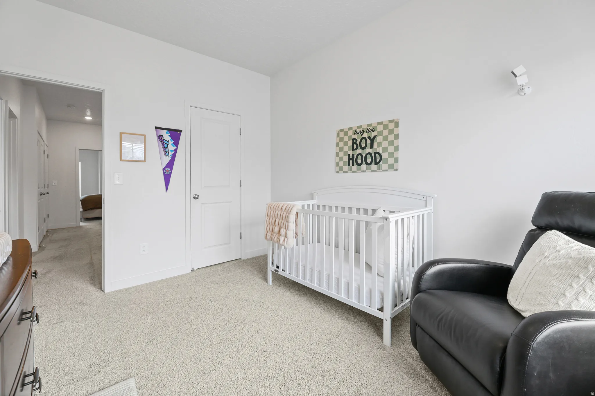 Carpeted room with white walls, a white paneled door, and a recessed doorway