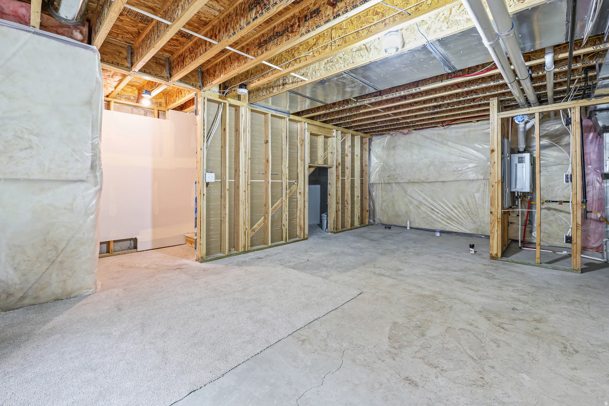 Unfinished basement area featuring exposed wood framing, concrete flooring, exposed ceiling joists, and visible utility lines