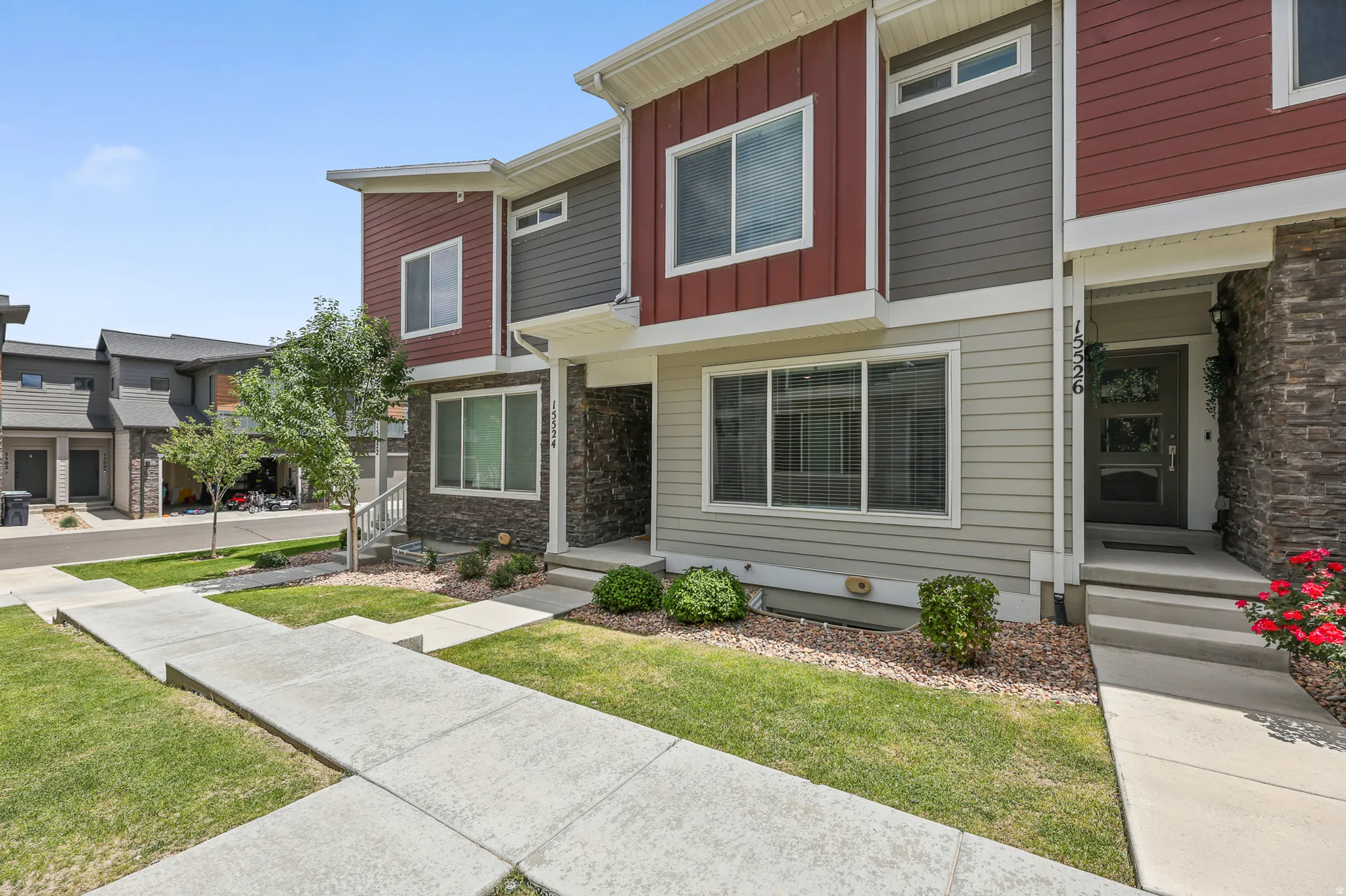 Contemporary townhome exterior featuring red and gray siding, stone accents, and a covered entry