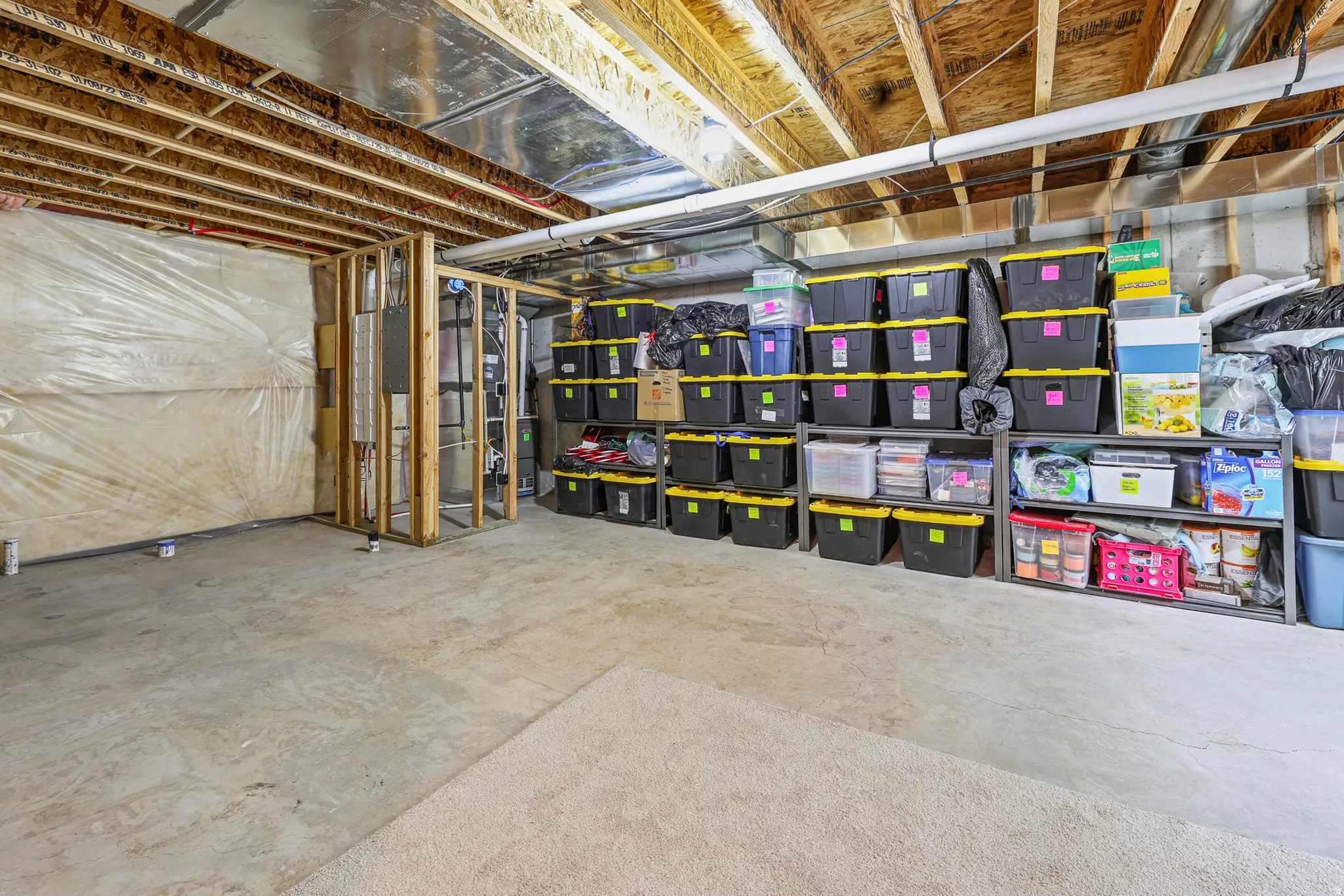 Unfinished basement area featuring exposed ceiling joists, concrete flooring, and partial wall framing