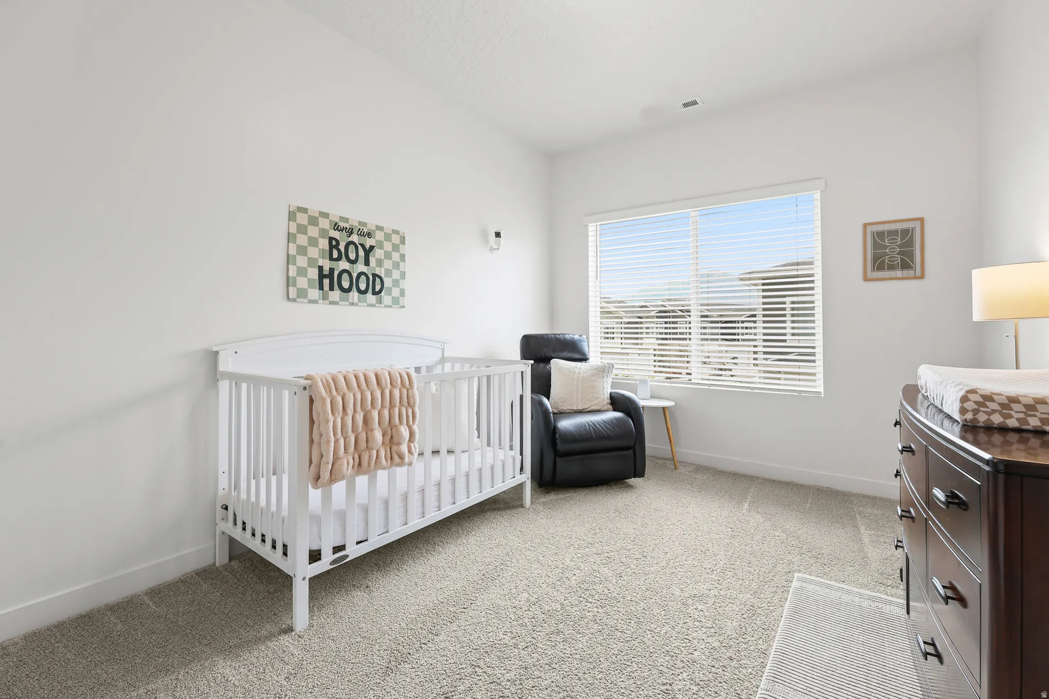Carpeted room with a wide window featuring horizontal blinds