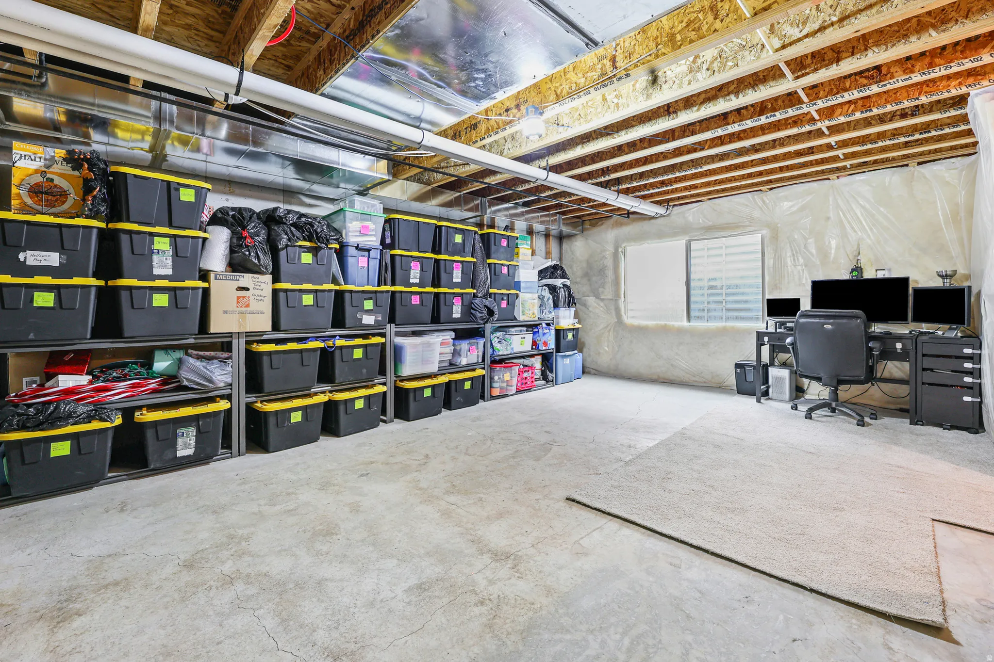 Unfinished basement space featuring exposed ceiling joists, concrete flooring, a window opening, and built-in shelving units