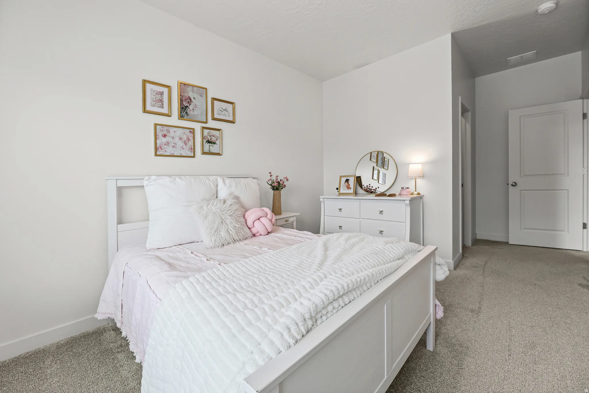 Carpeted room featuring a white paneled bed frame, white dresser with chrome pulls, and a white interior door
