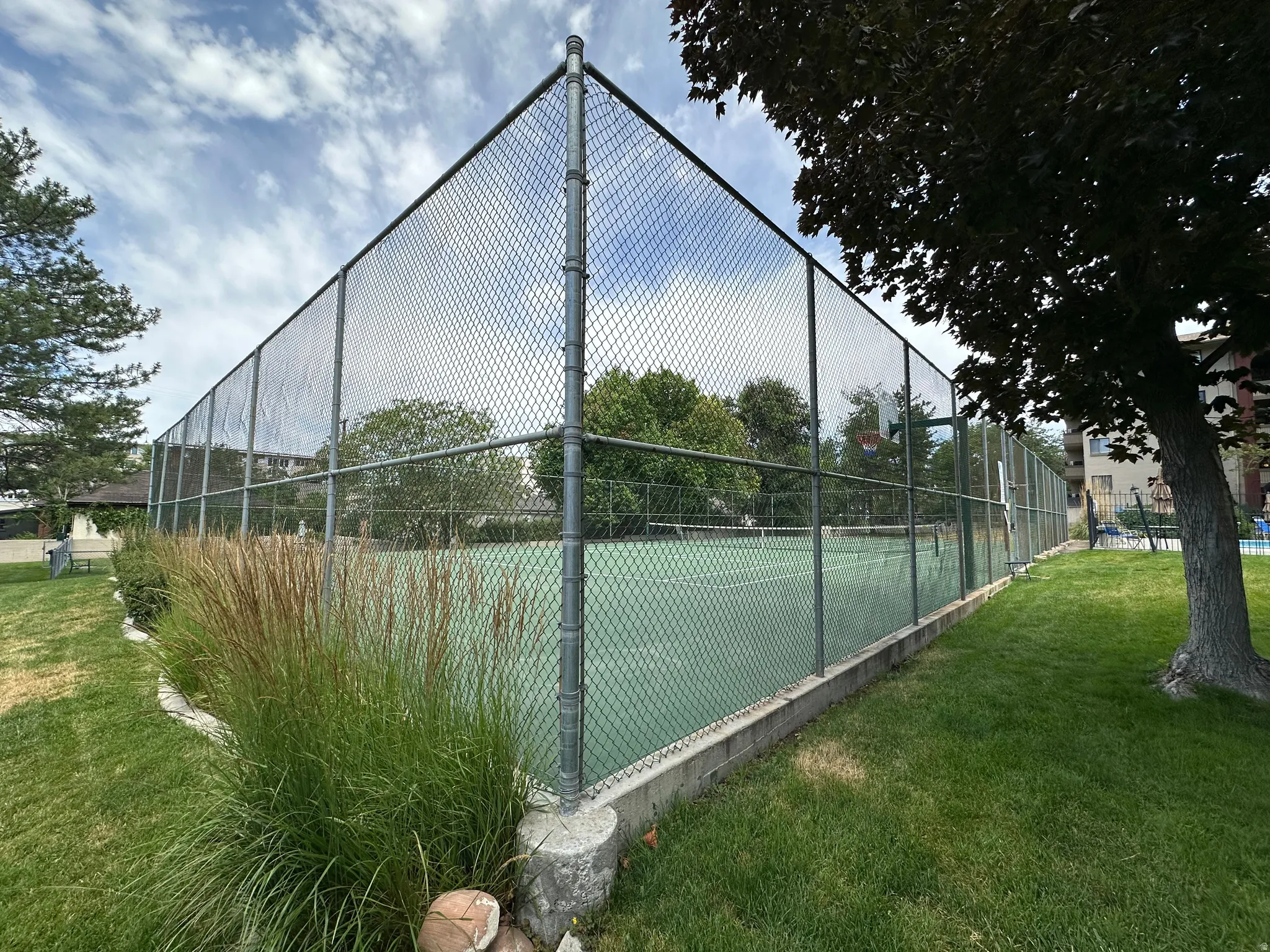 Outdoor recreational area featuring a green hardcourt surface with a chain-link fence enclosure