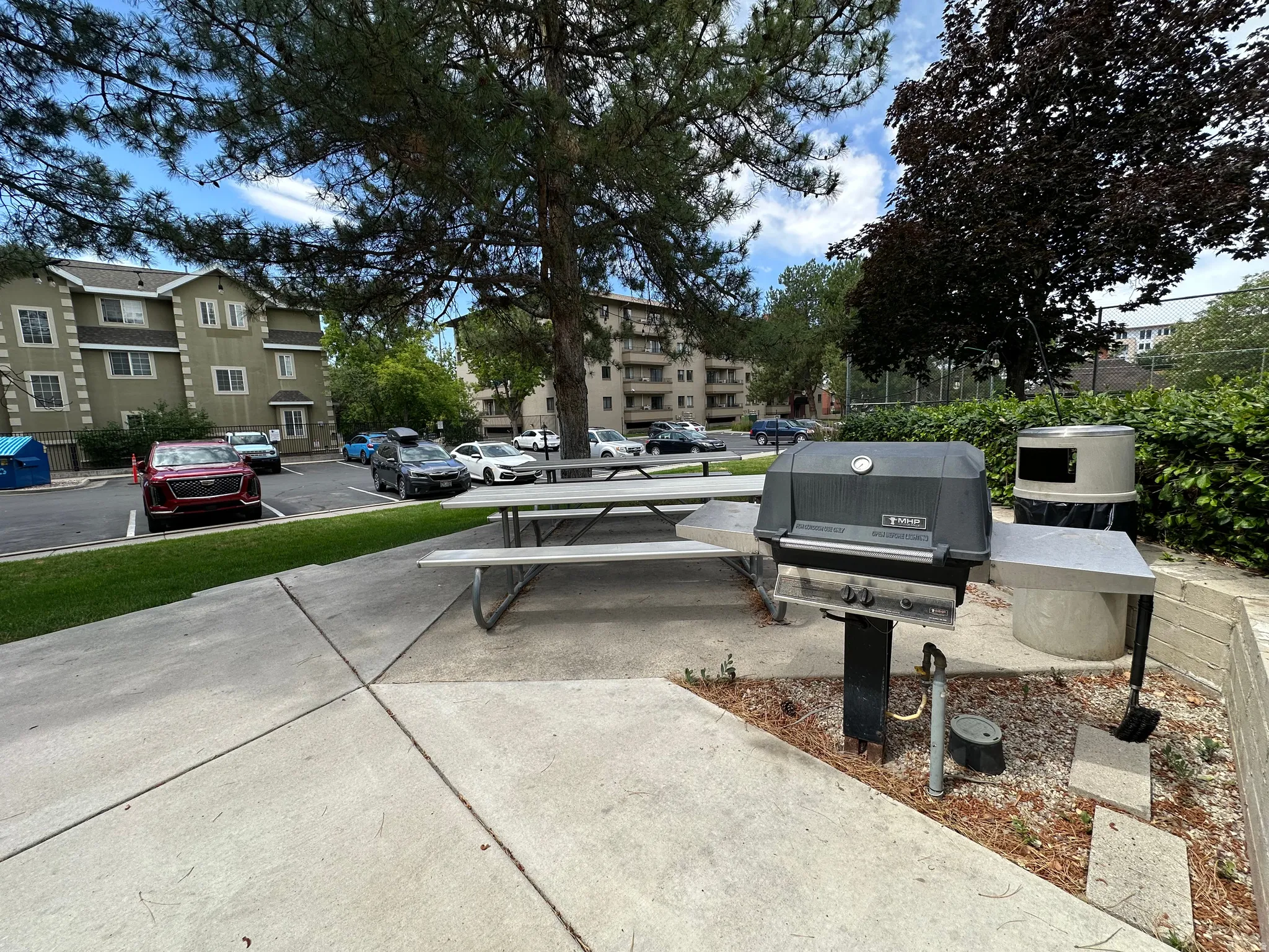 Outdoor grilling station featuring a built-in barbecue, adjacent picnic table, and surrounding concrete patio