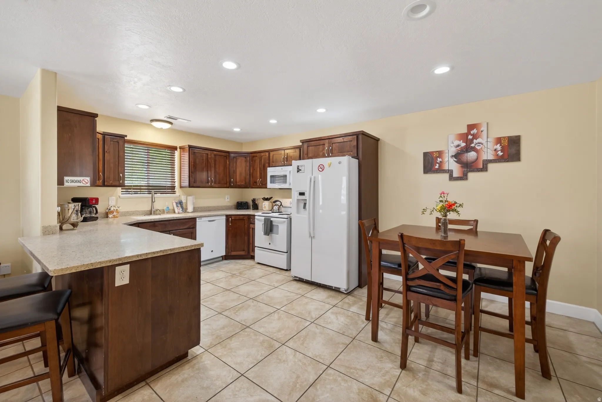 Kitchen featuring dark wood cabinetry, light speckled countertops, and tile flooring