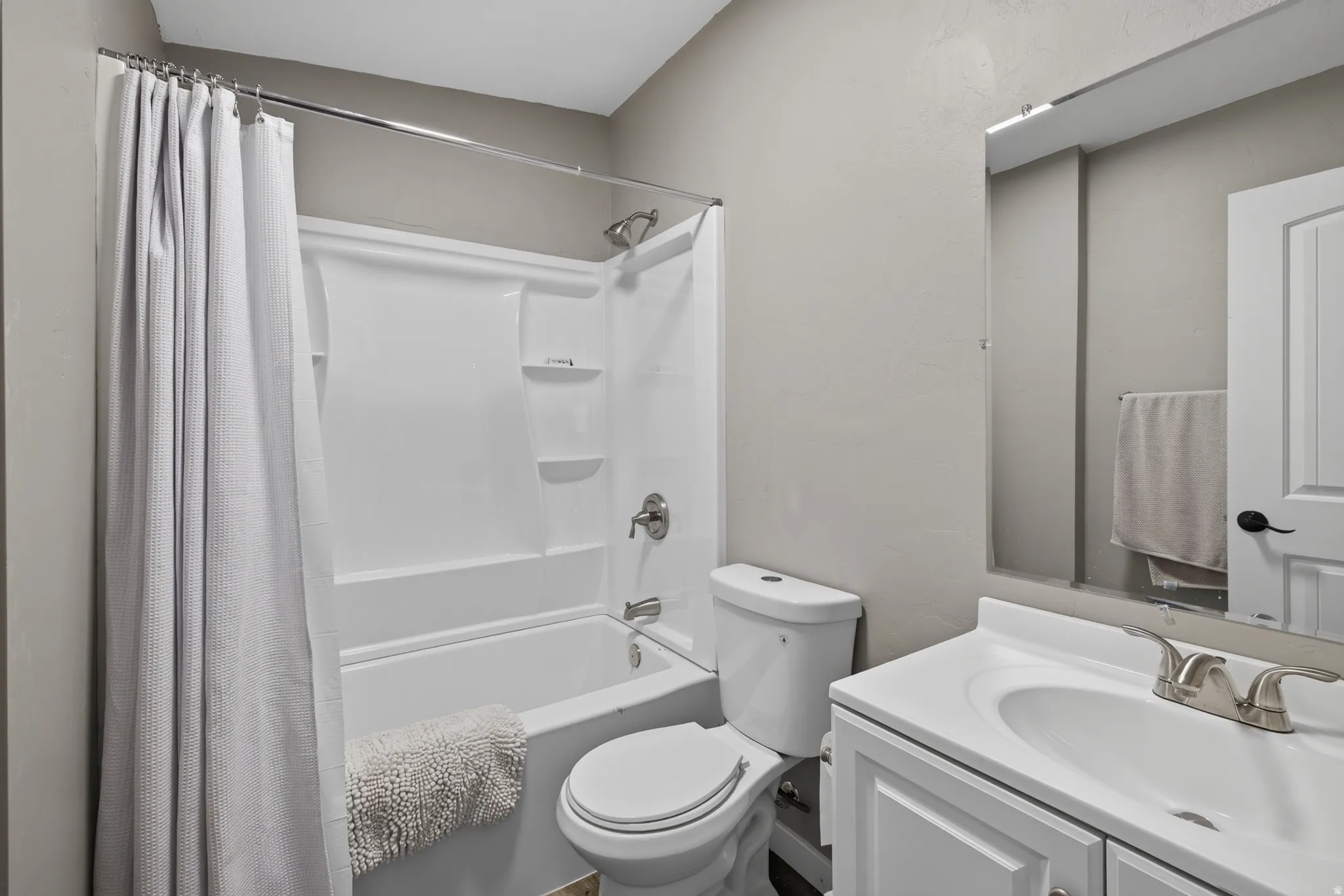 Bathroom featuring a white vanity with integrated sink, chrome faucet, and a large wall-mounted mirror