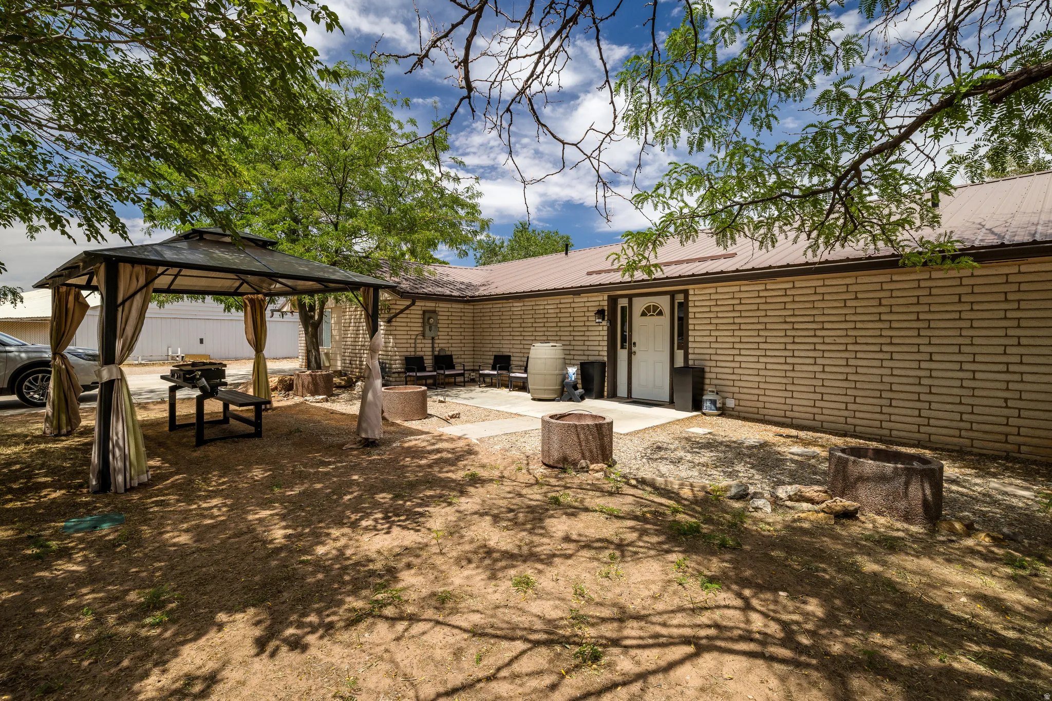 Exterior featuring a covered patio area with a gazebo, a brick facade, and a metal roof