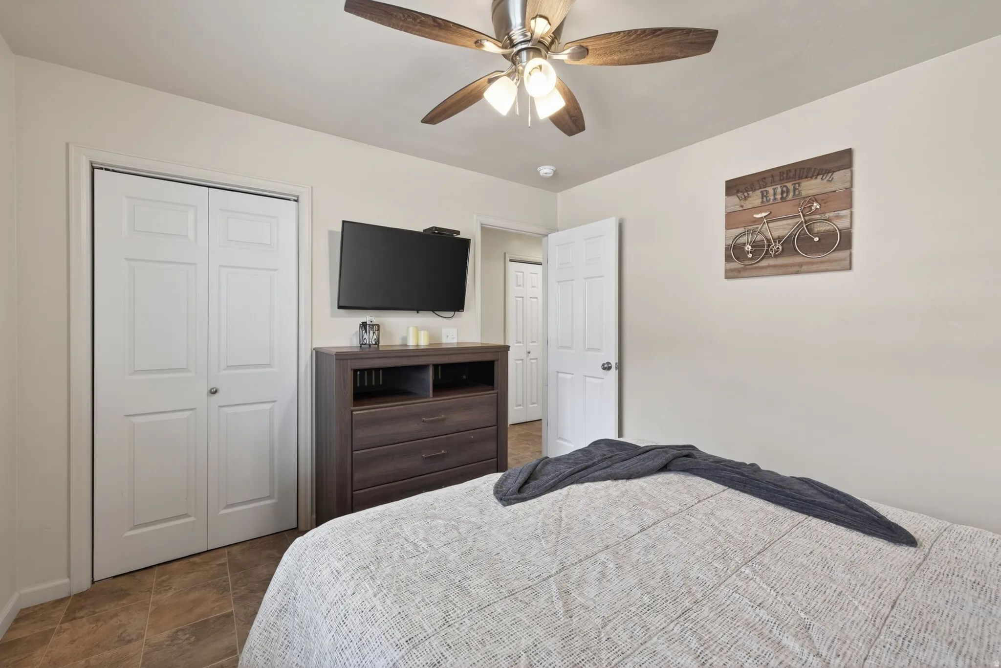 Bedroom featuring a ceiling fan with integrated lighting, a closet with bi-fold doors, and neutral wall tones