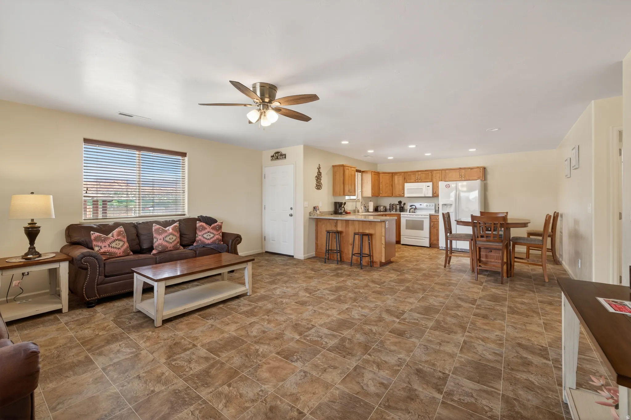 Open concept living space featuring a tiled floor, a ceiling fan, and a window with horizontal blinds
