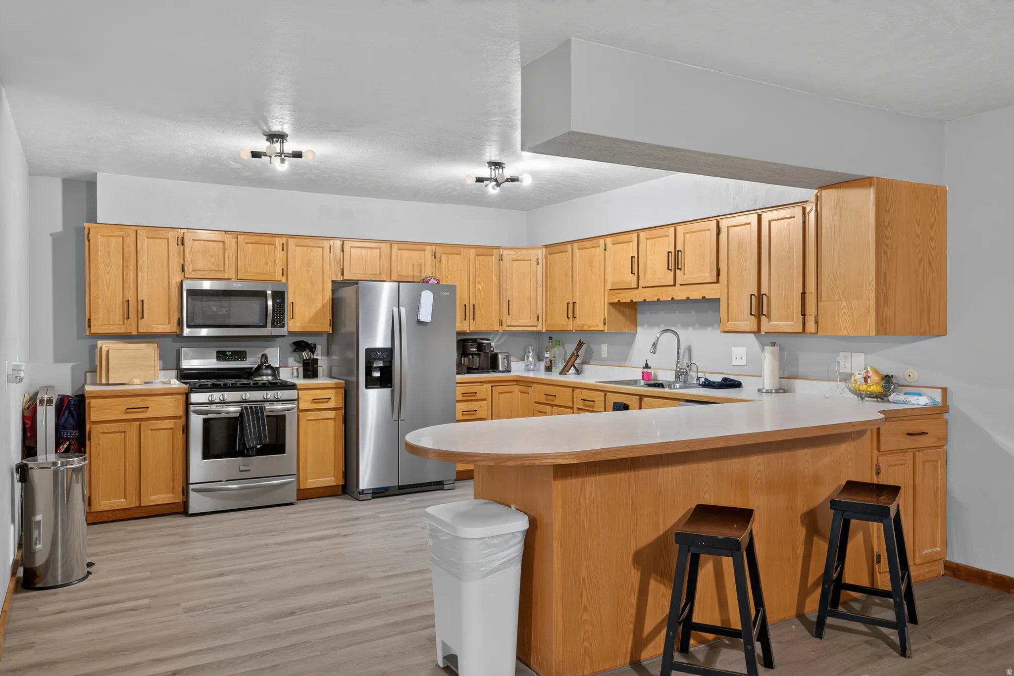 Kitchen featuring wood-finish cabinetry, stainless steel appliances, and a breakfast bar with a light-colored countertop