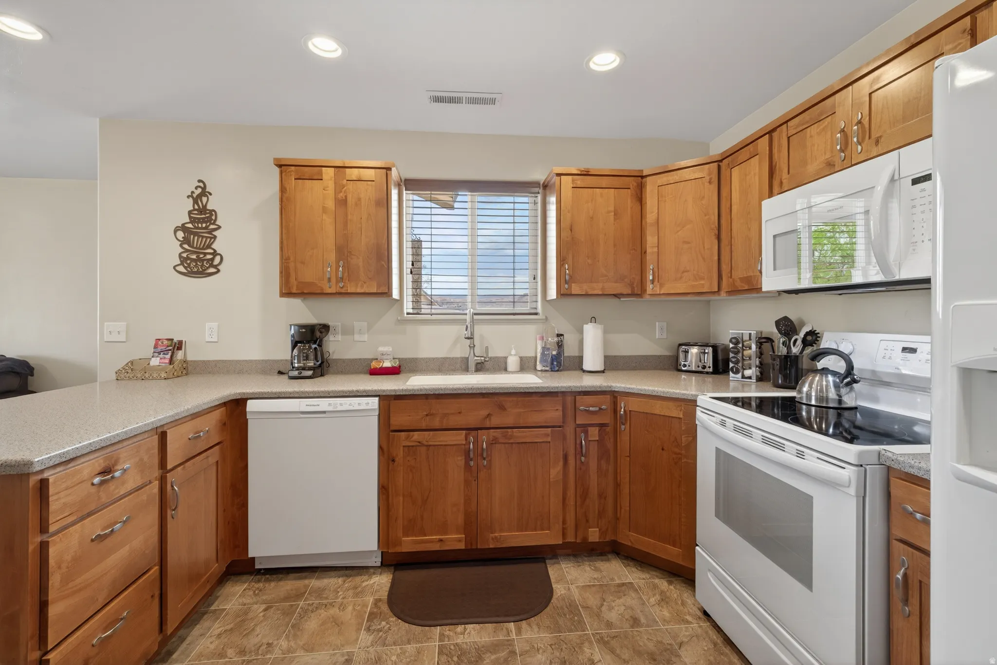 Full kitchen featuring wood cabinetry, solid surface countertops, a white dishwasher, and an electric range with an over-the-range microwave