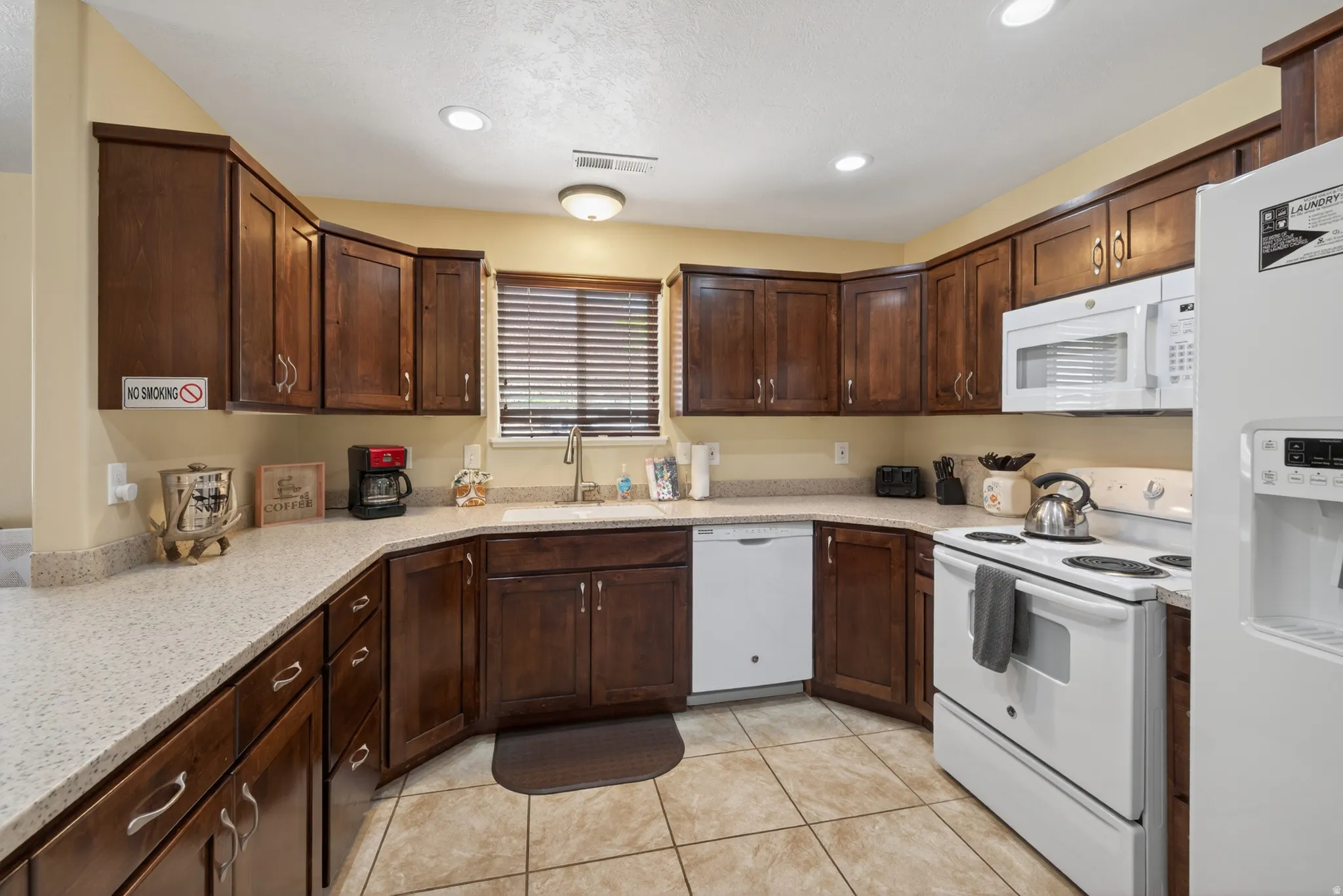 Kitchen featuring dark wood cabinetry, light speckled countertops, and tile flooring