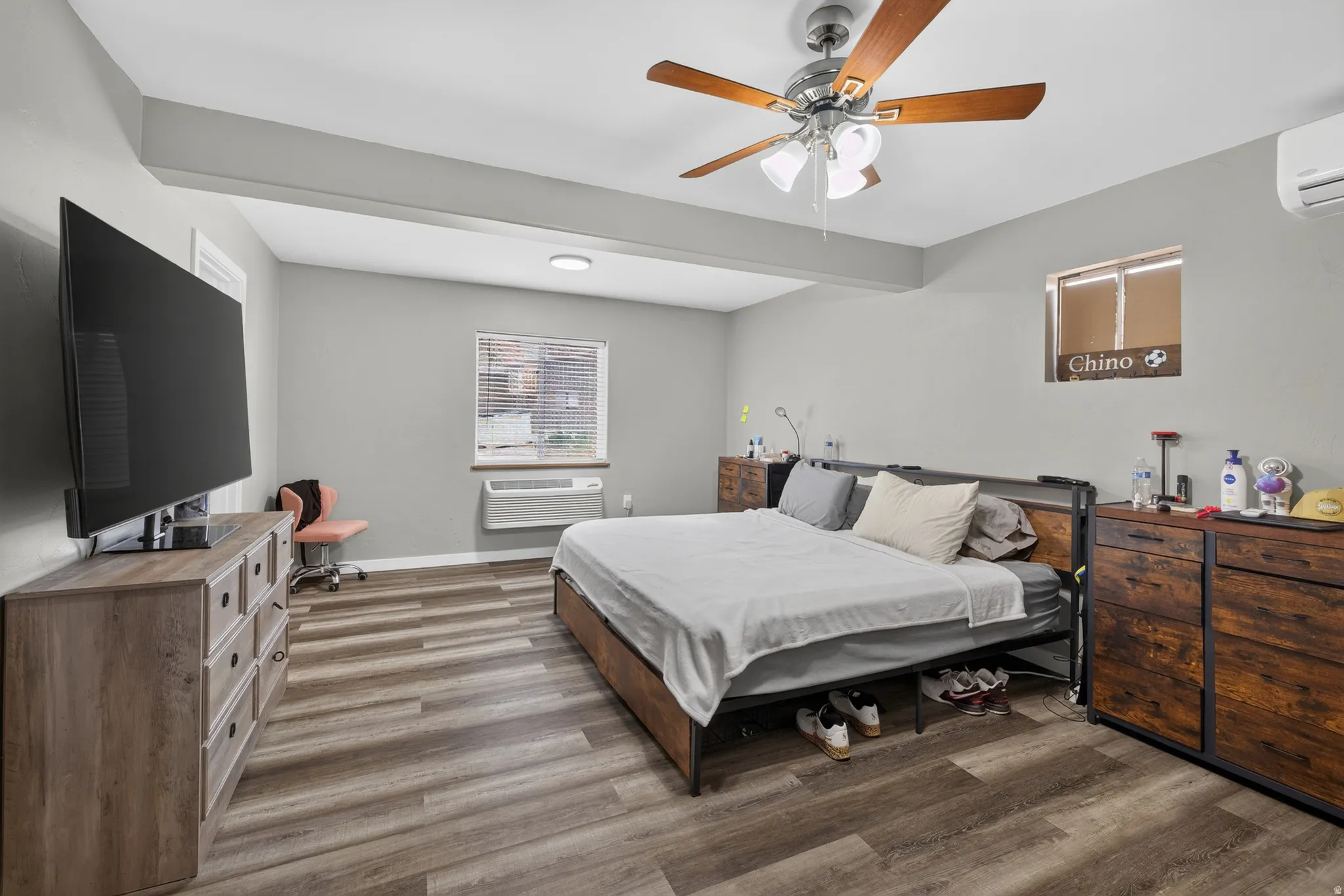 Spacious room featuring wood-finish flooring, a ceiling fan with integrated lighting, and neutral wall tones