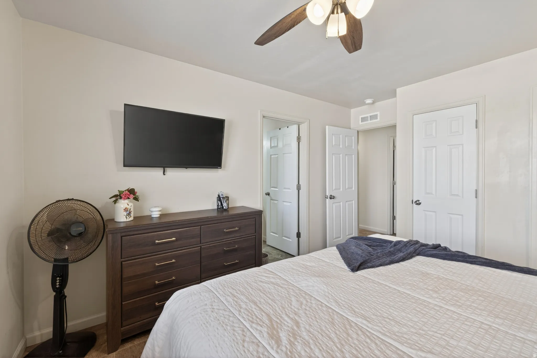 White paneled interior doors, a wood-finish ceiling fan with integrated lighting, and light-toned walls define this room