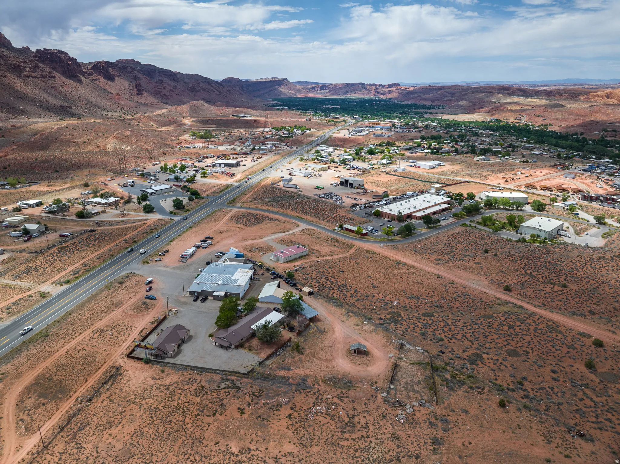 Expansive property featuring multiple structures, a paved road, and a large unpaved area