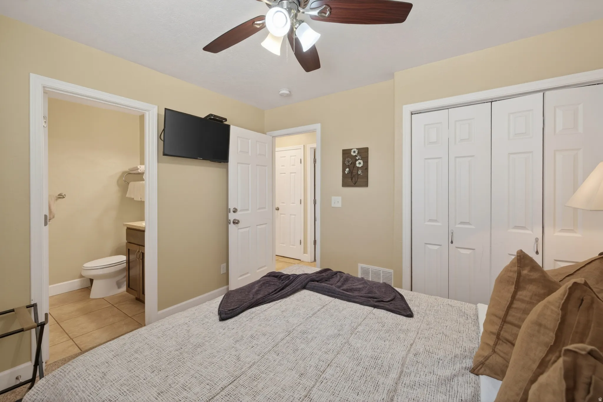 Bedroom featuring an attached bath, multi-panel closet doors, and a ceiling fan with integrated lighting