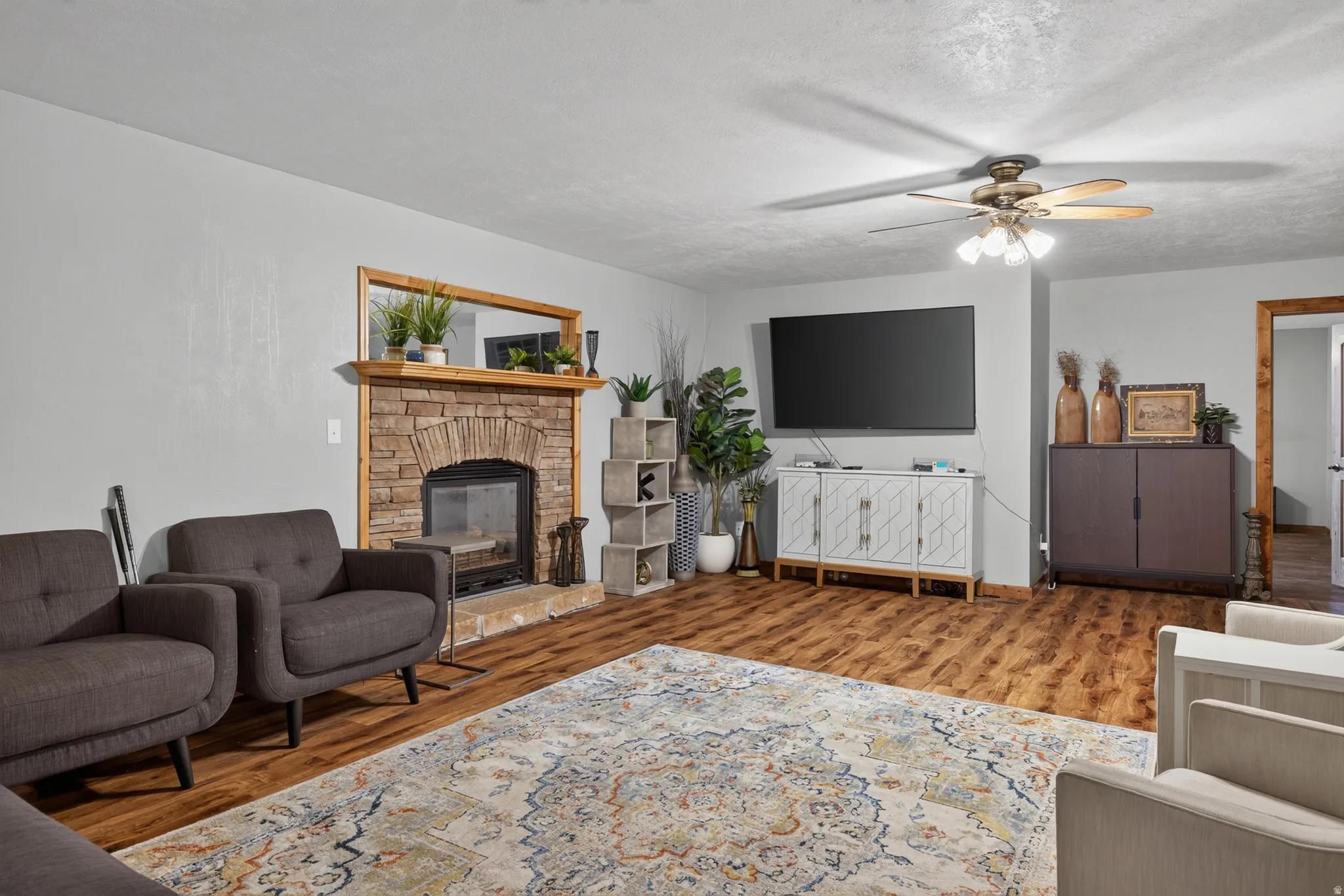 Living area featuring a stone-clad fireplace with wood mantel, wood-finish flooring, and light gray wall paint
