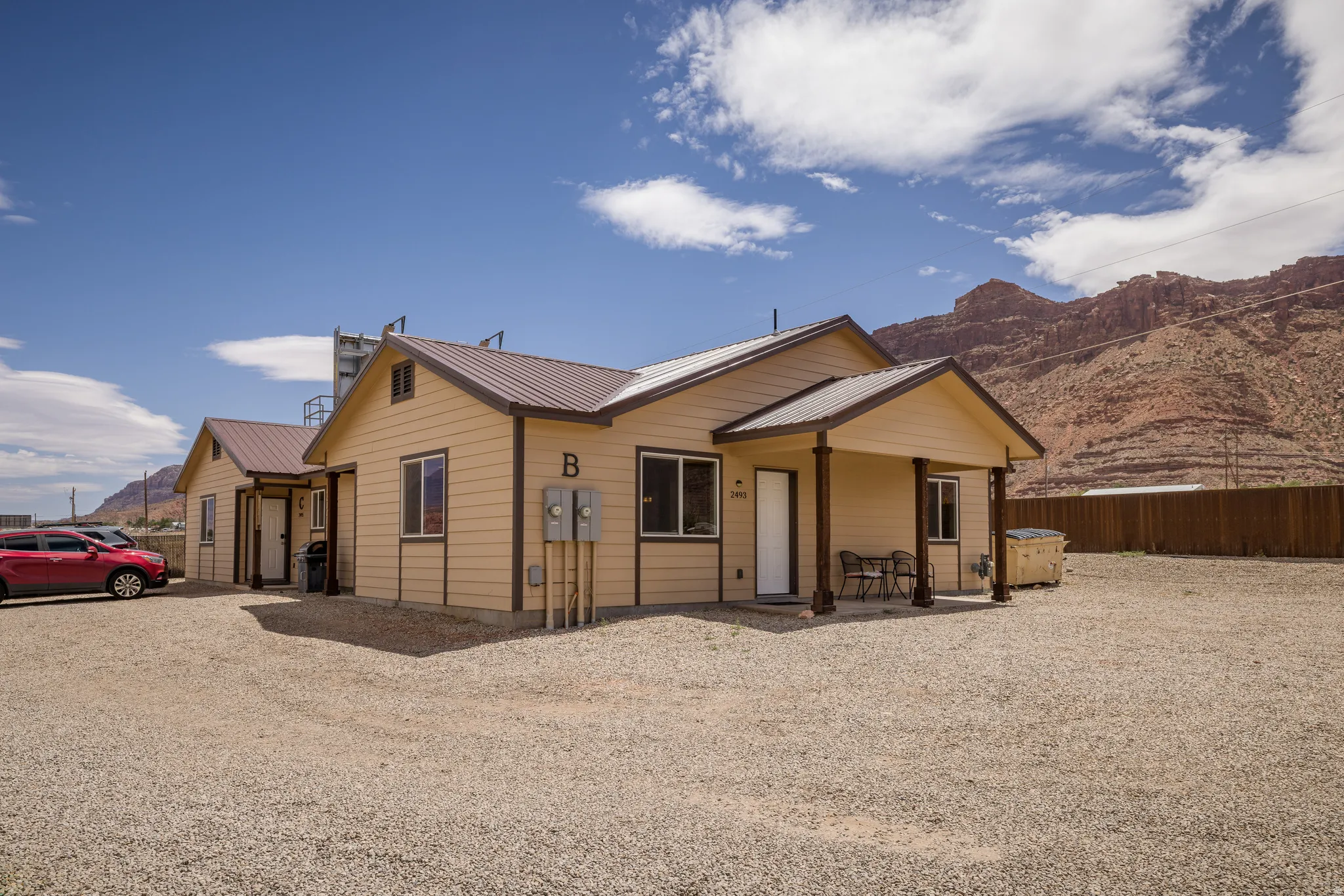 Two single-story structures with light tan siding and brown metal roofs