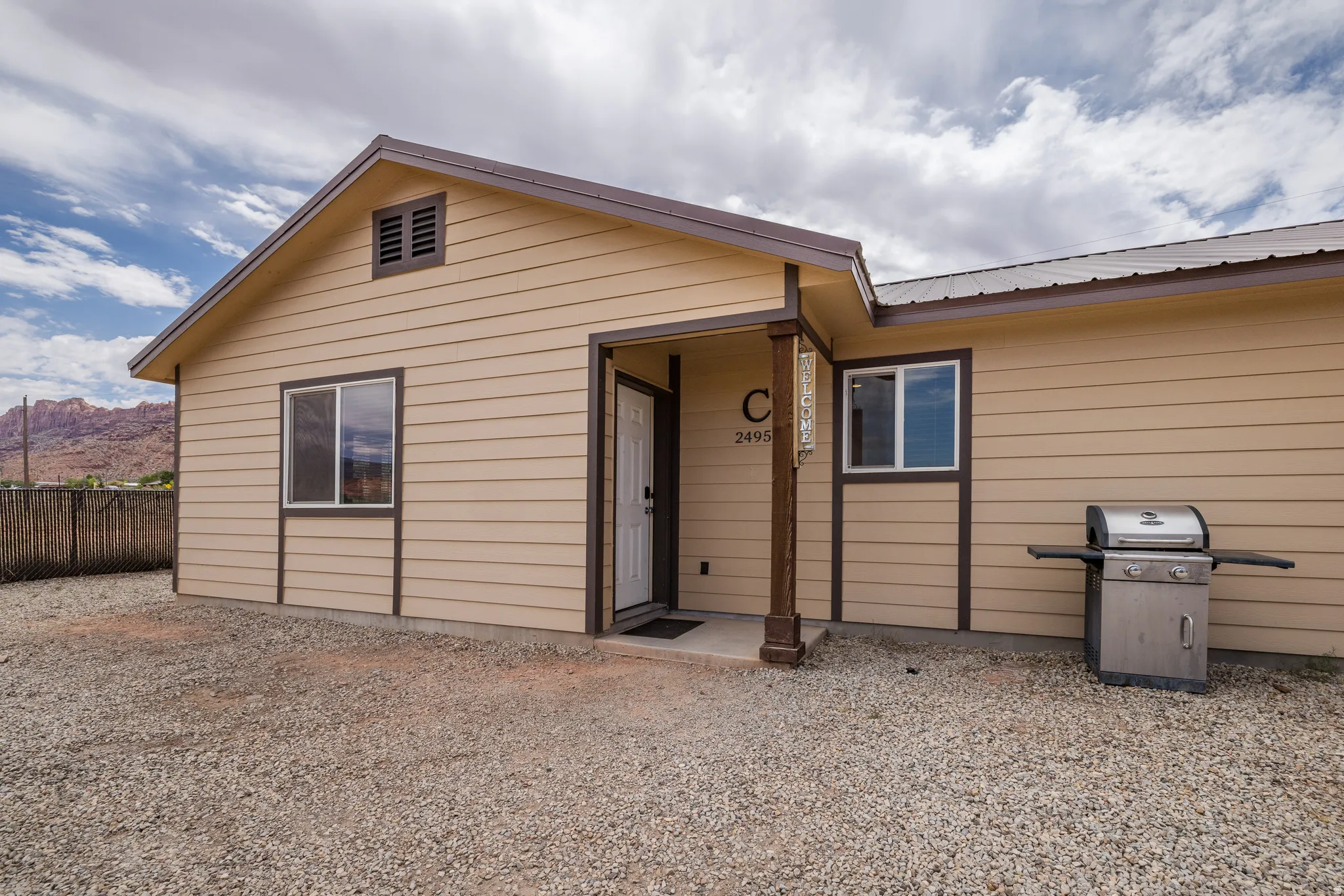 Tan siding exterior with brown trim accents and a metal roof