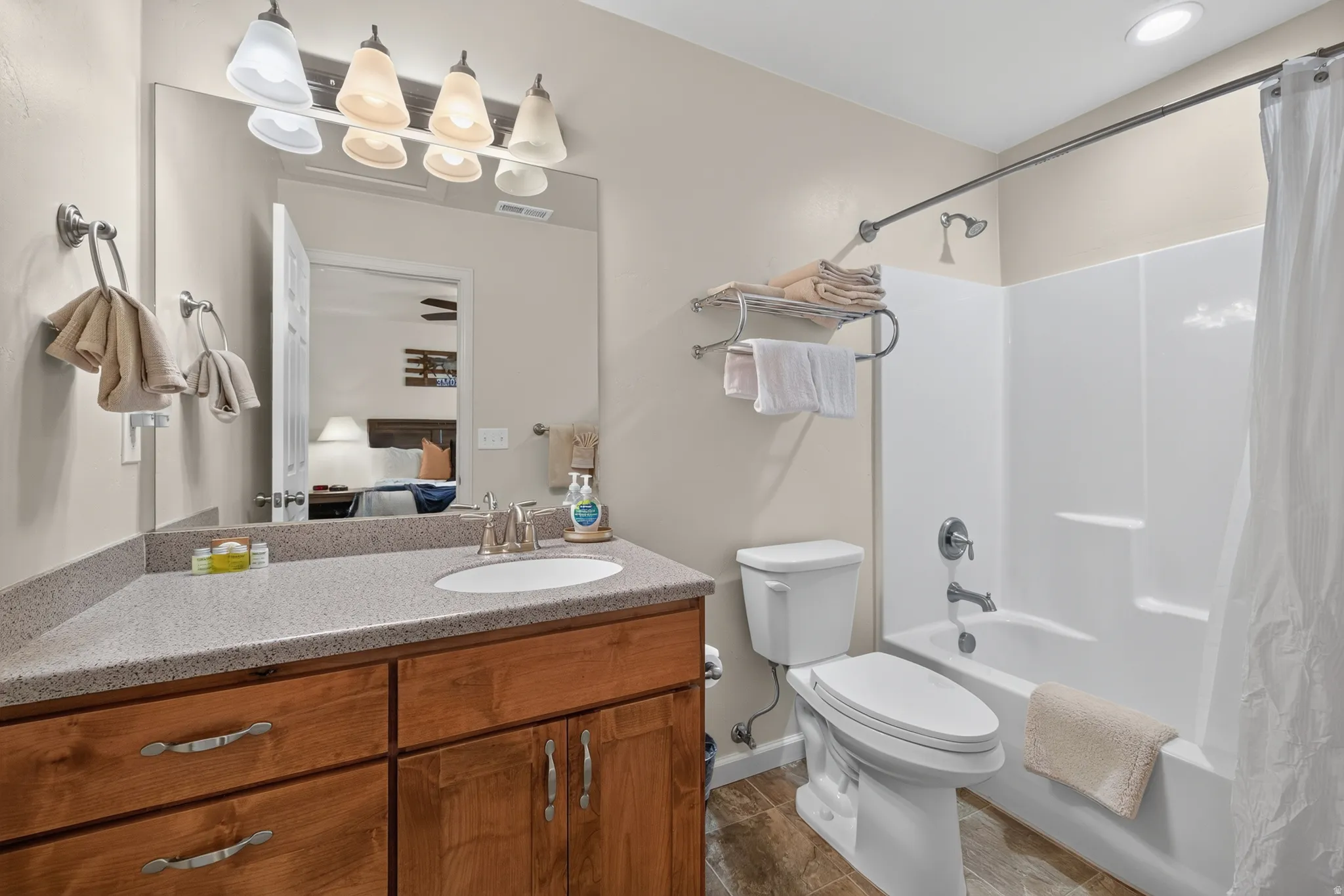 Bathroom featuring wood-finish flooring, a wood vanity with a light-colored countertop, and a white integrated sink