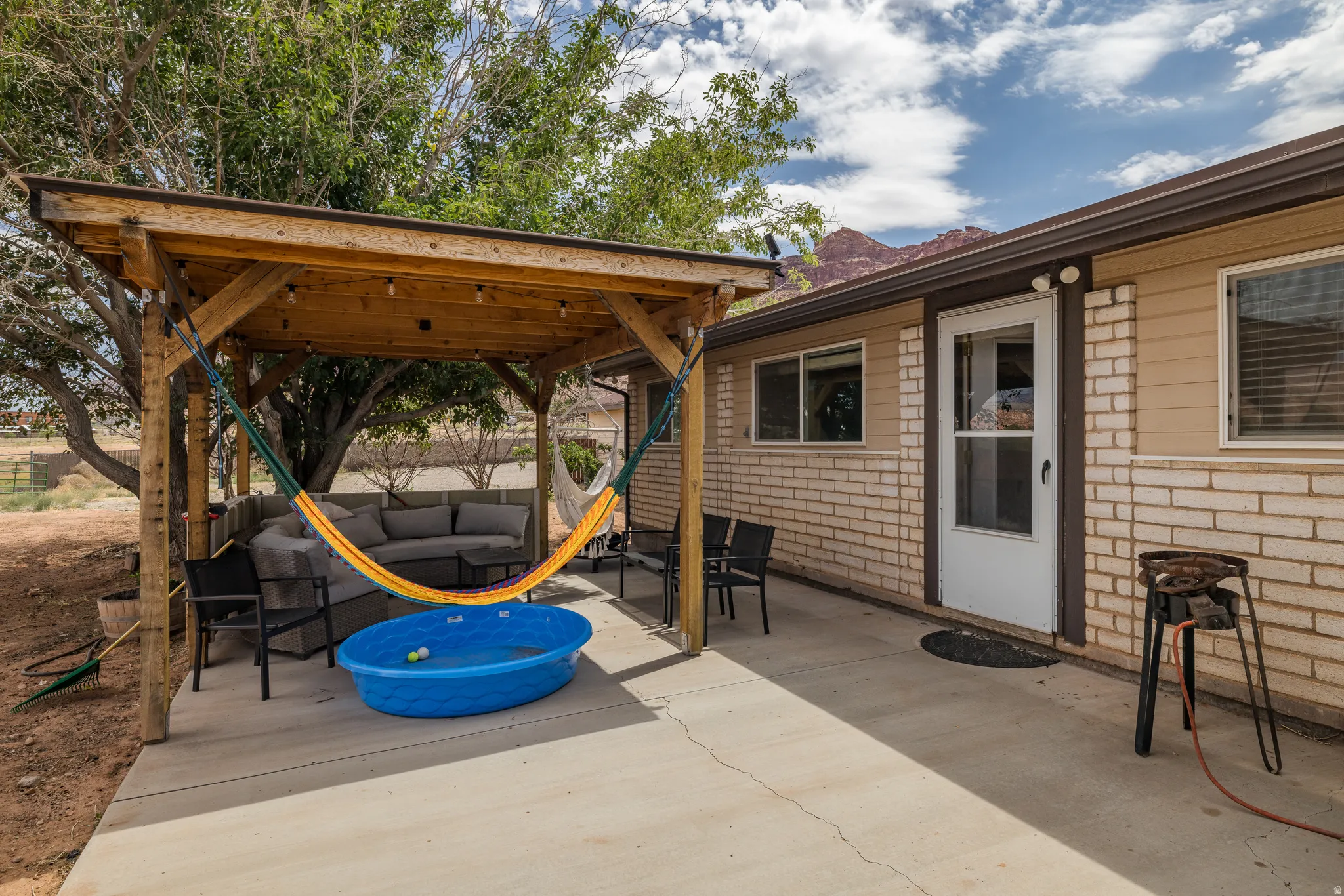 Outdoor living space featuring a wood-beam pergola with string lighting, a concrete patio, and a light brick and horizontal siding exterior