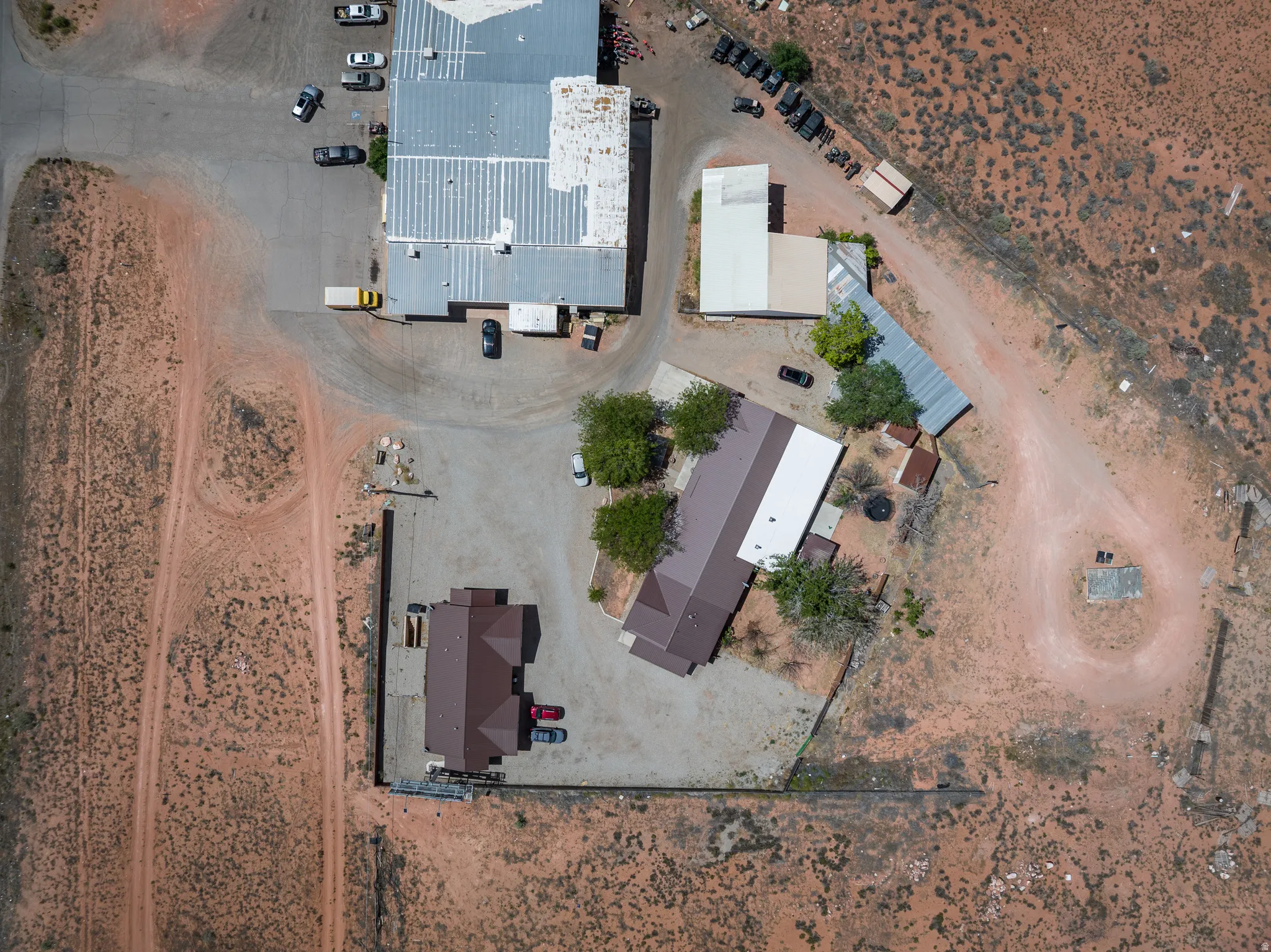 Aerial perspective showcasing multiple structures with varying rooflines and expansive surrounding land