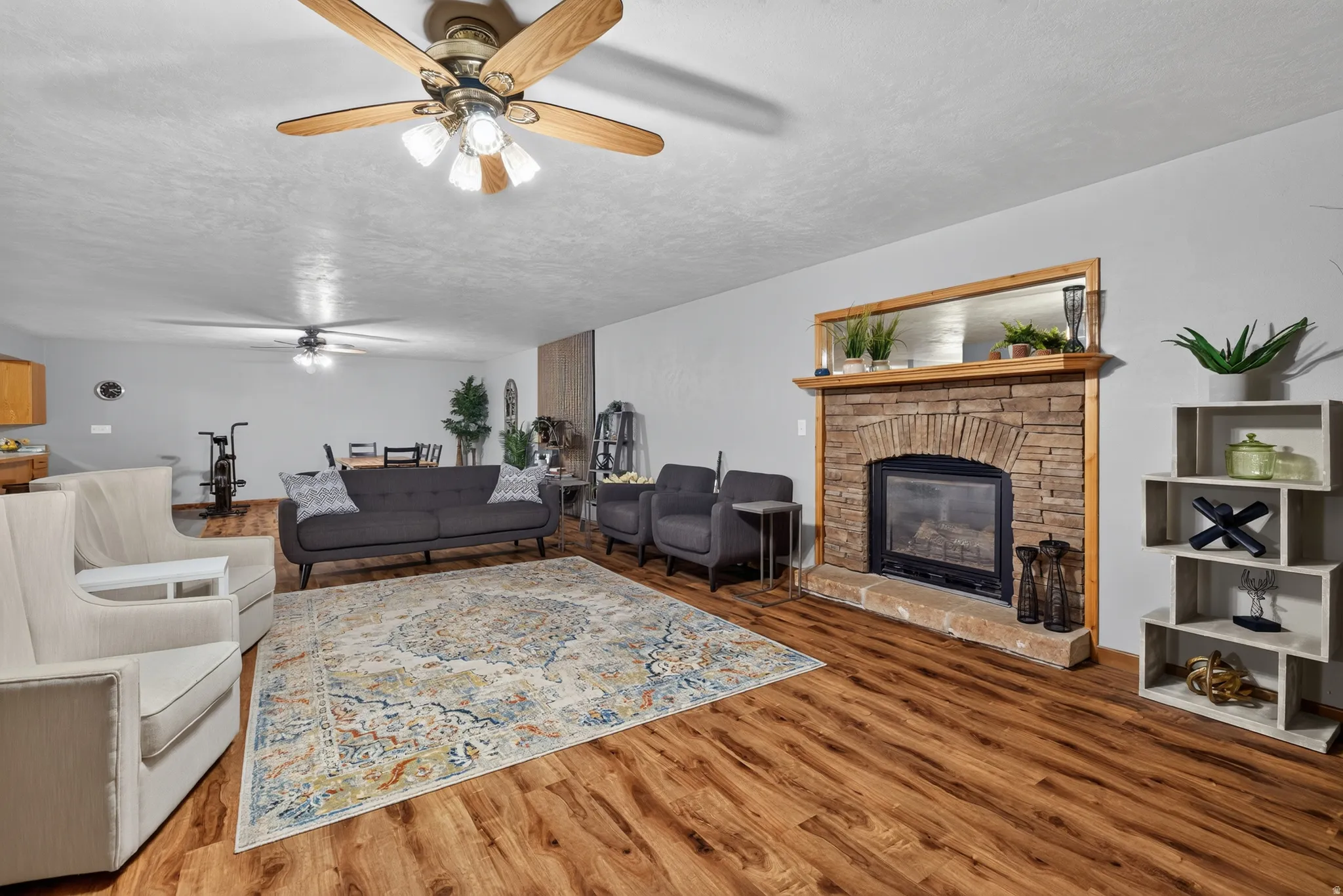 Spacious living area featuring wood-finish flooring and a stone-clad fireplace with a wood mantel