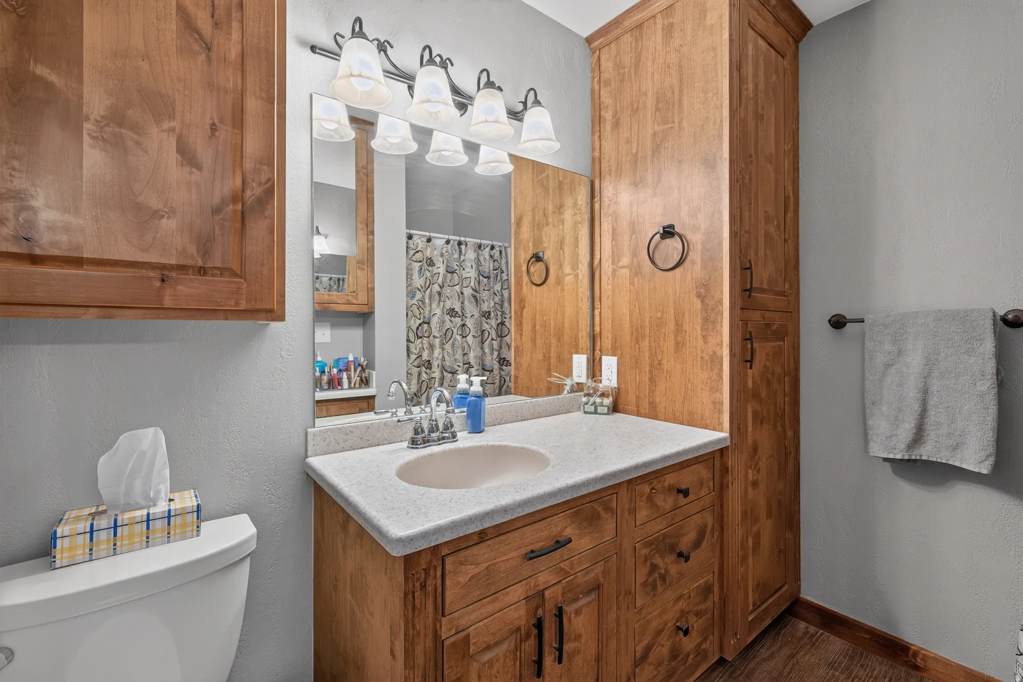 Bathroom featuring a single vanity with an integrated sink, a light-toned countertop, and wood-finish cabinetry