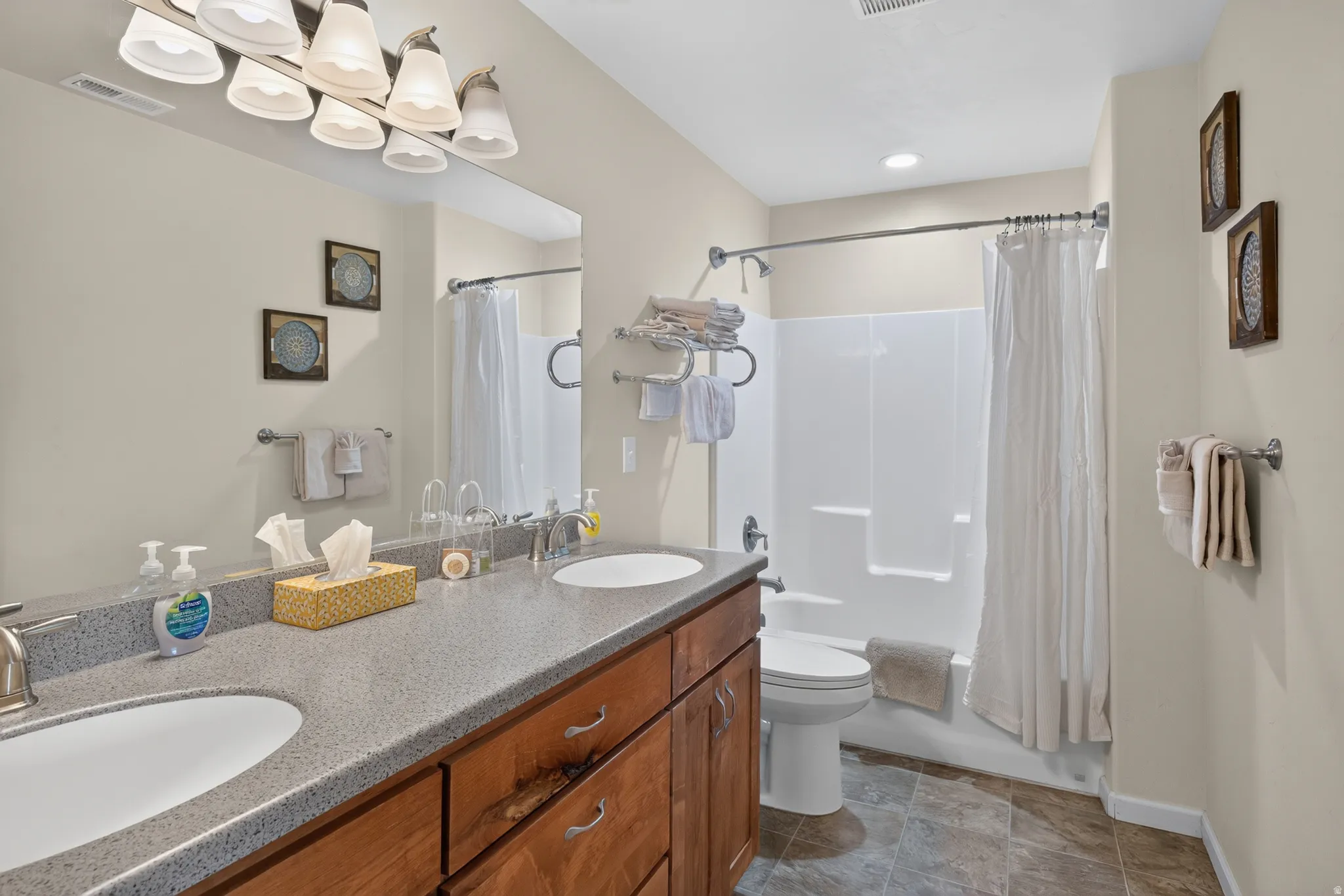Dual vanity featuring an integrated sink, wood-finish cabinetry, and a speckled countertop