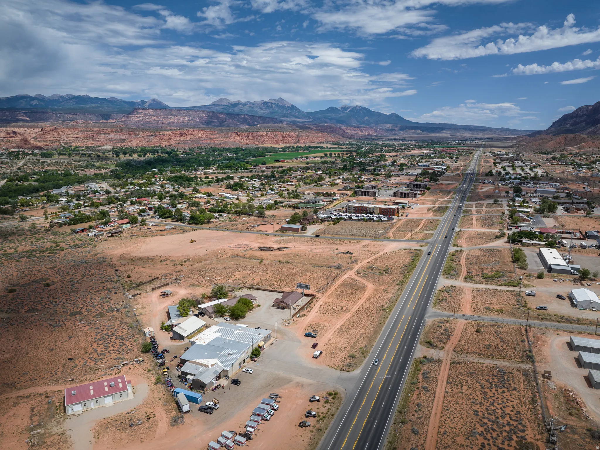 Expansive aerial perspective showcasing a commercial property with multiple structures, including a large building with a metal roof and an additional red-roofed structure