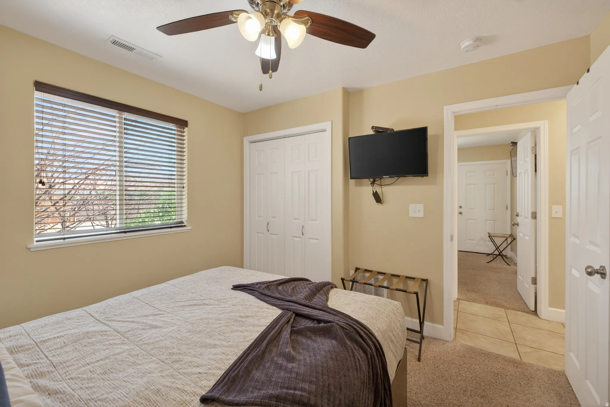Carpeted room with neutral wall tones and a window featuring horizontal blinds